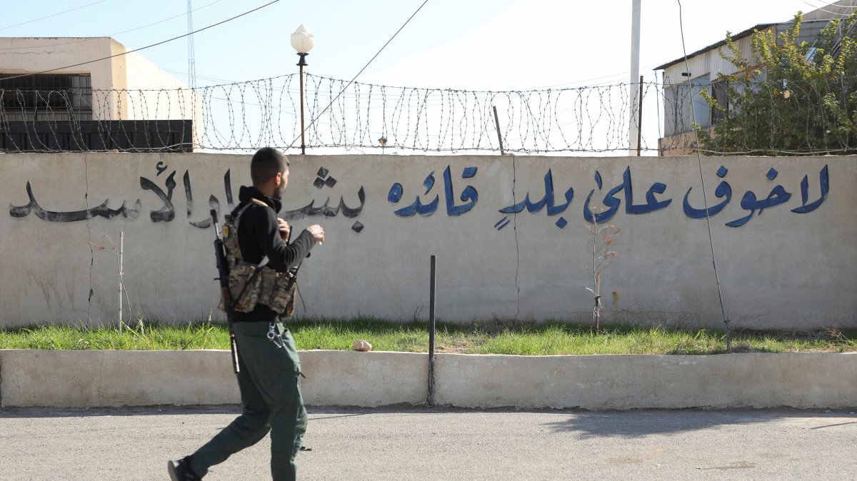 A member of the PKK/YPG terrorist group walks near writing on a wall that reads, &quot;There is no fear for a country whose leader is Bashar Assad,&quot; after anti-regime forces seized the capital and ousted Assad in Damascus, Qamishli, Syria, Dec. 9, 2024. (Reuters Photo)