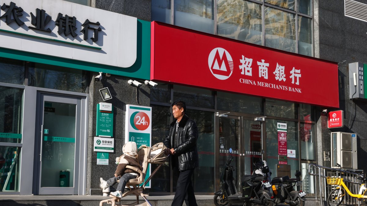 A man walks with a child past a bank in Beijing, China, Dec. 20, 2024. (EPA Photo)