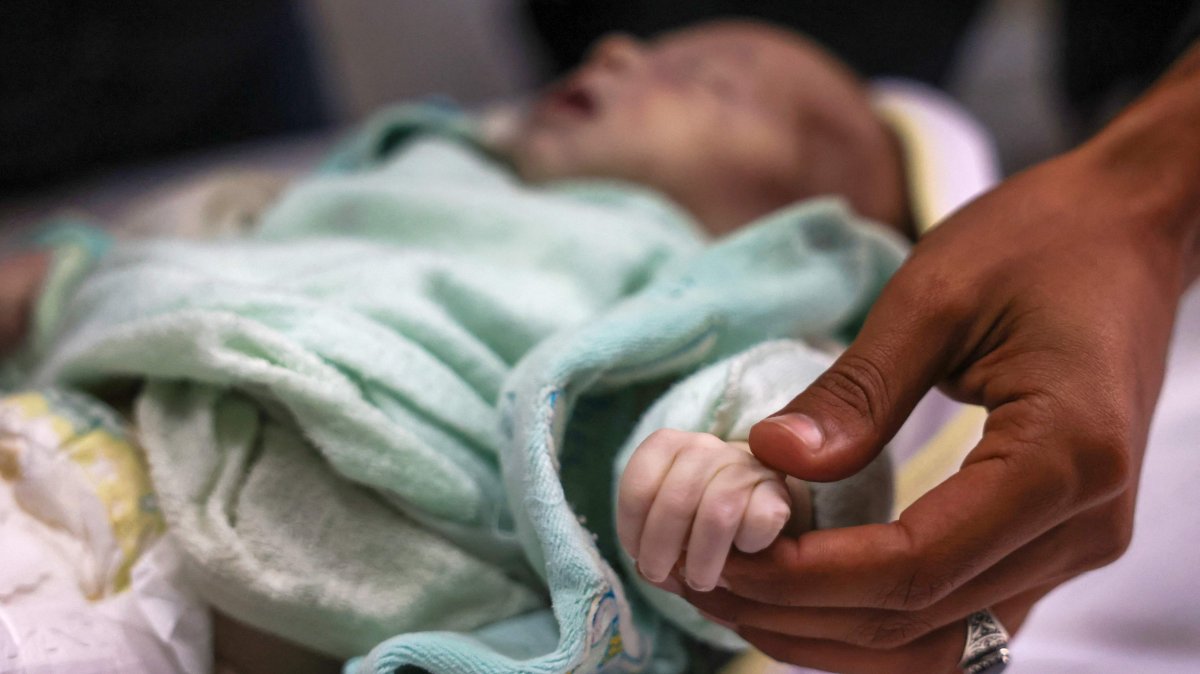 A Palestinian man holds the hand his niece 3-week old Sila al-Faseeh, who reportedly died of hypothermia, at the morgue of the Nasser Hospital in Khan Yunis, southern Gaza, Palestine, Dec. 25, 2024. (AFP Photo)