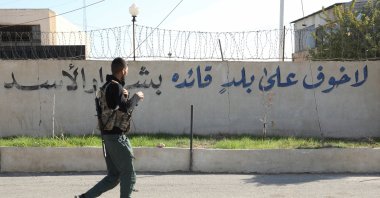 A member of the PKK/YPG terrorist group walks near writing on a wall that reads, &quot;There is no fear for a country whose leader is Bashar Assad,&quot; after anti-regime forces seized the capital and ousted Assad in Damascus, Qamishli, Syria, Dec. 9, 2024. (Reuters Photo)