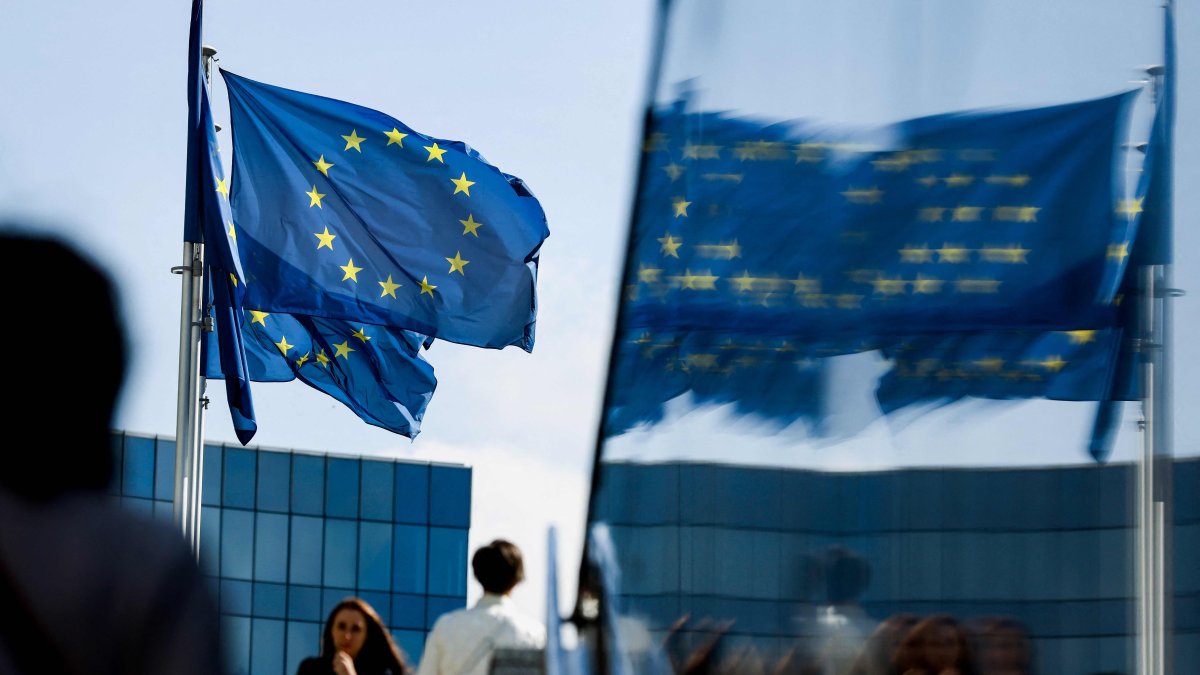 People walk in front of the European Union flag in the area of the EU headquarters in Brussels, Belgium, Sept. 23, 2021. (AFP Photo)