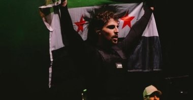 Renowned musician Saint Levant raises the Syrian flag during his concert. (Saint Levant on Instagram)