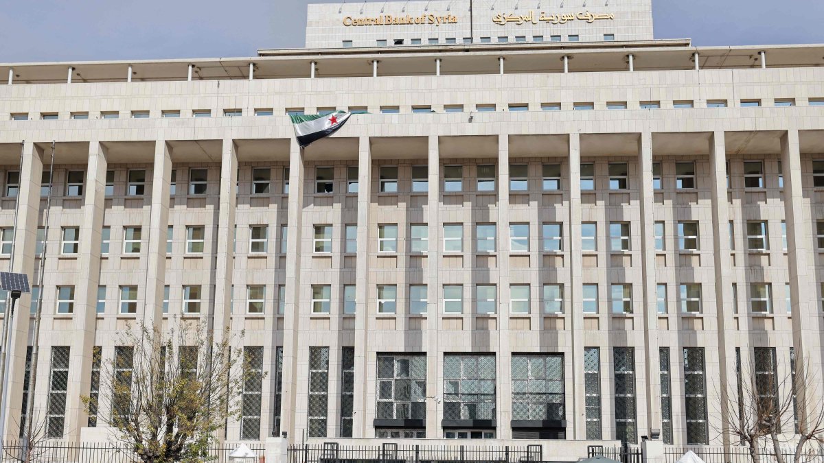 Vehicles move past as people queue outside the main headquarters of the Central Bank of Syria to exchange U.S. dollars at prices lower than the black market, Damascus, Syria, Dec. 30, 2024. (AFP Photo)