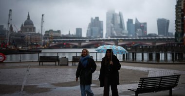 People walk along the South Bank with the buildings of the City of London financial district in the background, London, U.K., Dec. 13, 2024. (AFP Photo)