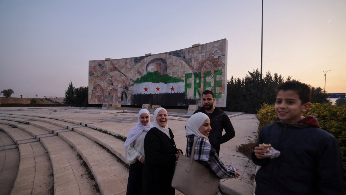 People stand near graffiti of the Syrian flag painted on a mosaic of former Syrian regime leader Hafez Assad after the ousting of Bashar Assad, Damascus, Syria, Jan. 2, 2025. (Reuters Photo)