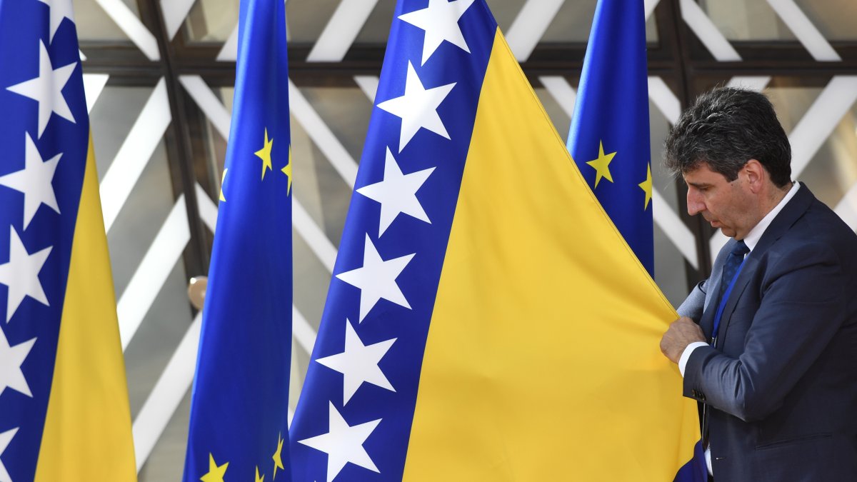 A member of protocol adjusts the Bosnia-Herzegovina flag before arrivals at an EU summit in Brussels, Thursday, June 23, 2022. (AP File Photo)