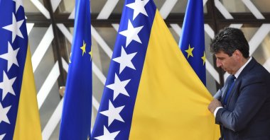A member of protocol adjusts the Bosnia-Herzegovina flag before arrivals at an EU summit in Brussels, Thursday, June 23, 2022. (AP File Photo)