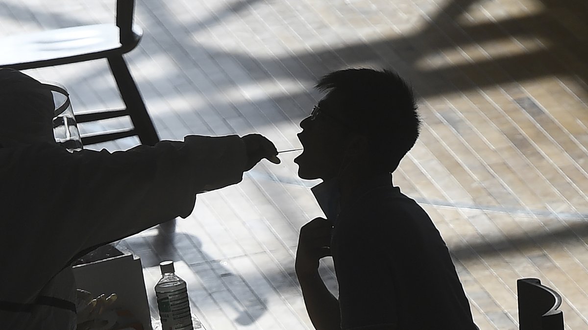 A medical worker takes a swab sample from a worker of the China Star Optoelectronics Technology (CSOT) company during a round of COVID-19 tests in Wuhan in central Hubei province, China, Aug. 5, 2021. (AP Photo)