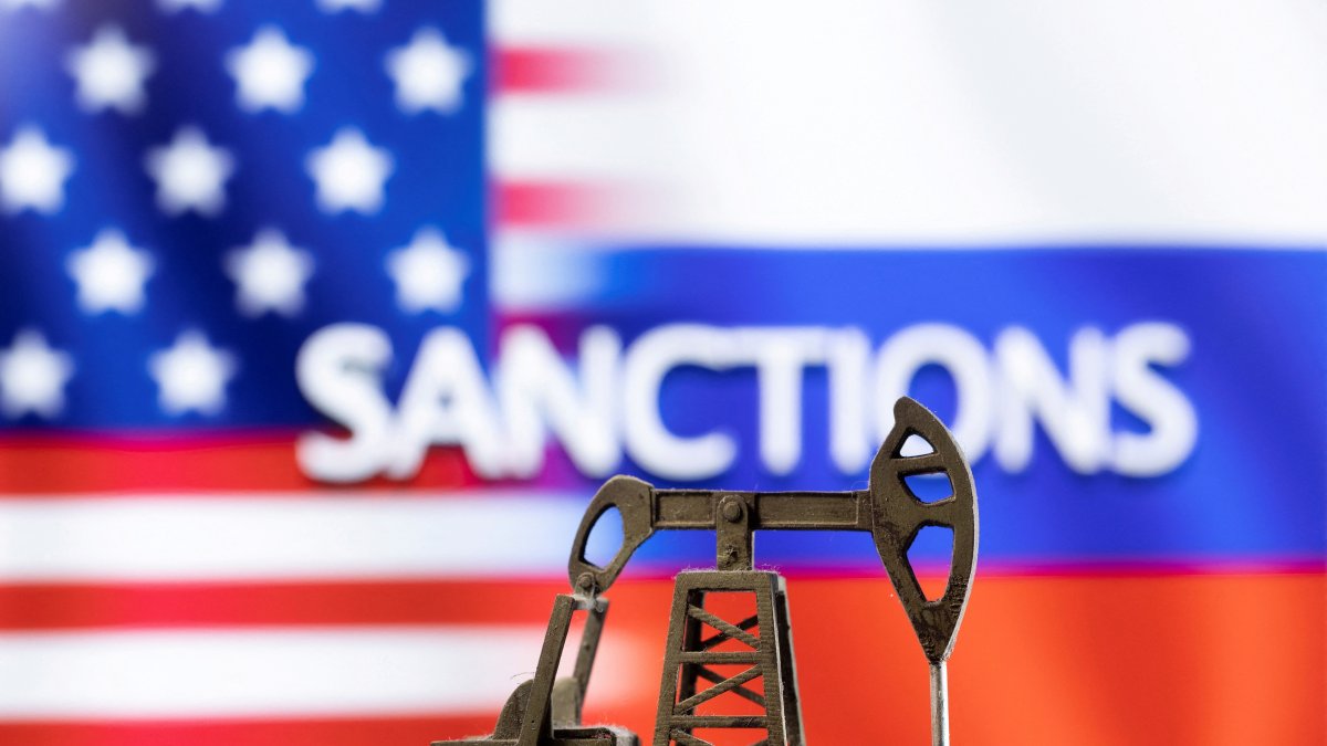 A model of a pump jack is seen in front of the displayed word &quot;Sanctions&quot; and U.S. and Russia flag colors in this illustration created on March 8, 2022. (Reuters Photo)