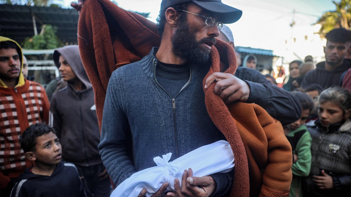 A Muslim cleric wraps a blanket around the father of newborn Jumaa al-Batran, who reportedly died due to hypothermia, in Deir el-Balah, central Gaza Strip, Dec. 29, 2024. (AFP Photo)