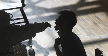 A medical worker takes a swab sample from a worker of the China Star Optoelectronics Technology (CSOT) company during a round of COVID-19 tests in Wuhan in central Hubei province, China, Aug. 5, 2021. (AP Photo)