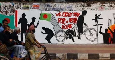 Commuters on a rickshaw pass by graffiti illustrating the Student Movement of 2024, Dhaka, Bangladesh, Jan. 1, 2025. (Reuters Photo)