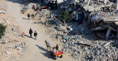 Palestinians ride a donkey-drawn cart as others walk past the rubble of houses destroyed in Israeli attacks, Khan Younis, southern Gaza Strip, Palestine, Jan. 7, 2025. (Reuters Photo)