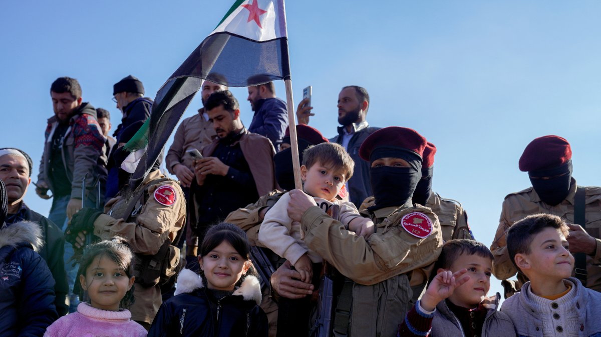 A member of the Syrian National Army (SNA) holds a child after fighters of the now ruling Syrian body ousted Syria&#039;s Bashar Assad, Aleppo, Syria, Dec. 13, 2024. (Reuters Photo)