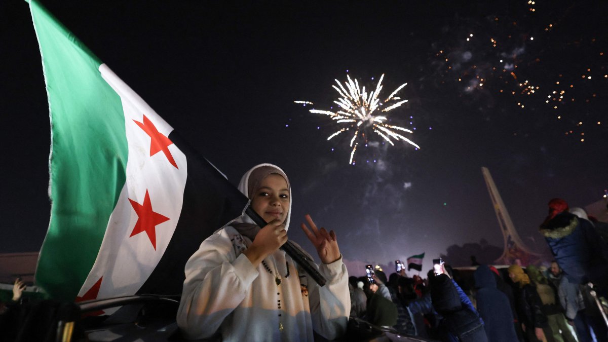 A young woman holds the Flag of Syria as people celebrate the New Year near Umayyad Square in Damascus, Syria, Jan. 1, 2025. (AFP Photo)