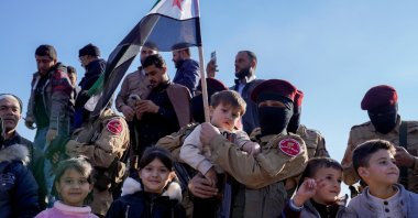 A member of the Syrian National Army (SNA) holds a child after fighters of the now ruling Syrian body ousted Syria's Bashar Assad, Aleppo, Syria, Dec. 13, 2024. (Reuters Photo)
