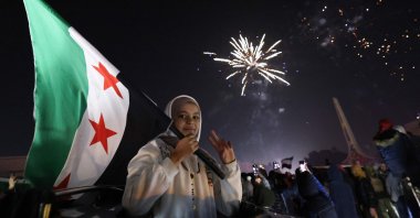 A young woman holds the Flag of Syria as people celebrate the New Year near Umayyad Square in Damascus, Syria, Jan. 1, 2025. (AFP Photo)