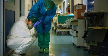 A nurse wearing a protective mask and gear comforts another as they change shifts, Milan, Italy, March 13, 2020. (AFP Photo)