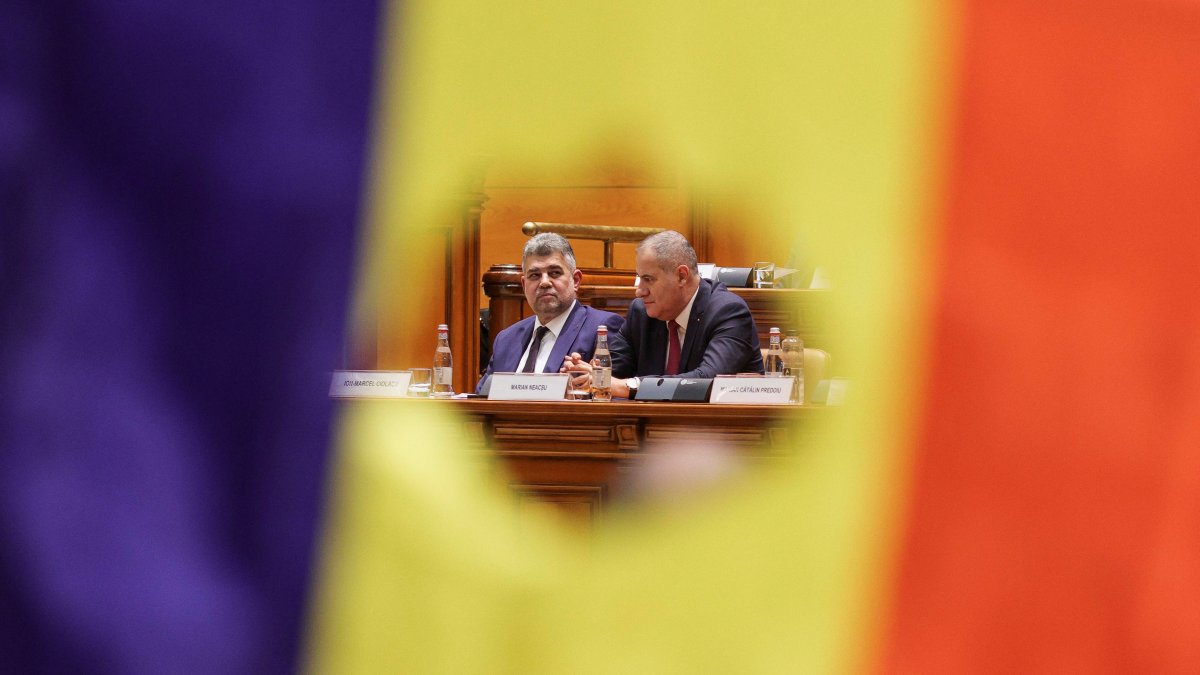 Social Democrat Party (PSD) leader and Prime Minister-designate Marcel Ciolacu and a minister are visible through a cut out of the Romanian flag, recalling the Romanian Revolution flag, during a Parliament session for a vote of confidence of the new coalition government, Bucharest, Romania, Dec. 23, 2024. (Reuters Photo)