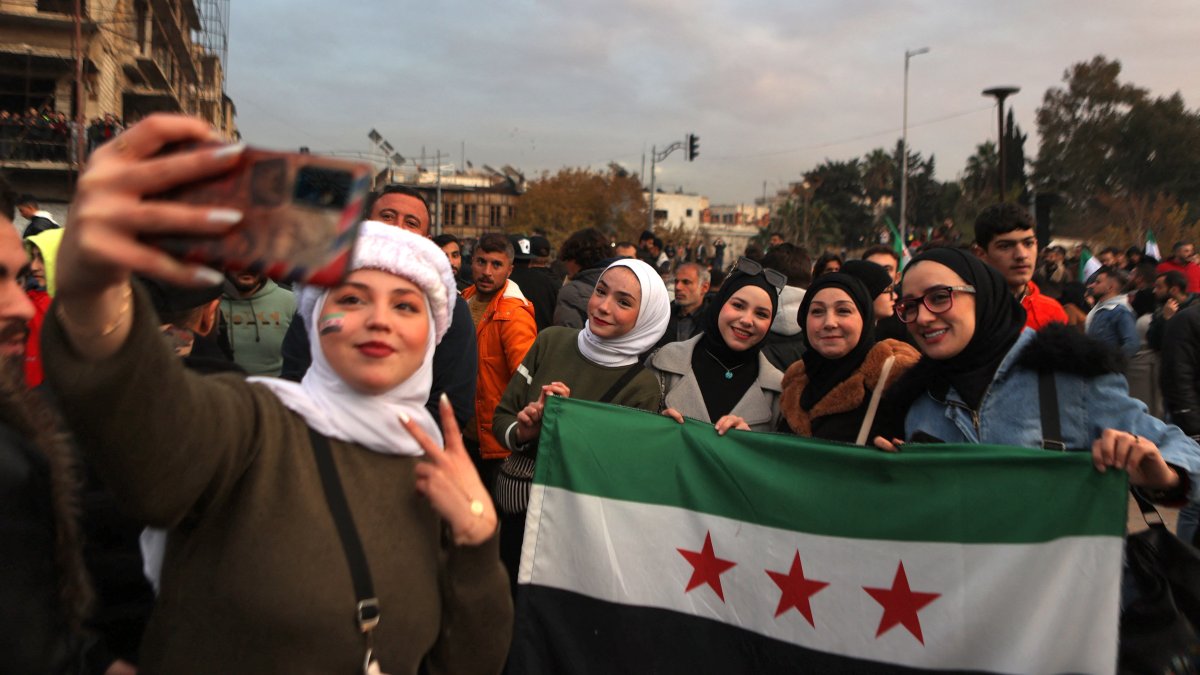 Women take a selfie holding an independence-era flag as they take part in the &quot;Liberation Festival&quot; celebrating the fall of Bashar Assad, Aleppo, Syria, Dec. 21, 2024. (AFP Photo)