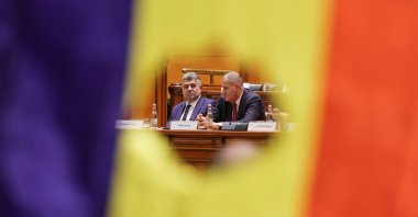 Social Democrat Party (PSD) leader and Prime Minister-designate Marcel Ciolacu and a minister are visible through a cut out of the Romanian flag, recalling the Romanian Revolution flag, during a Parliament session for a vote of confidence of the new coalition government, Bucharest, Romania, Dec. 23, 2024. (Reuters Photo)