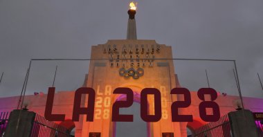 An LA 2028 sign is seen in front of a blazing Olympic cauldron at the Los Angeles Memorial Coliseum, Sept. 13, 2017. (AP Photo)