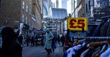 Pedestrians look at stands as they walk down Petticoat Lane Market, with the City of London financial district in the distance, central London, U.K., Jan. 9, 2025. (AFP Photo)
