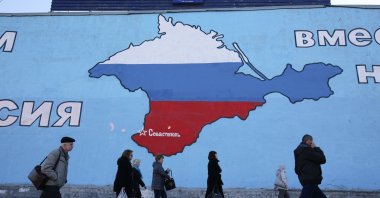 Pedestrians pass a giant wall mural showing a map of the Crimean Peninsula filled with the flag of the Russian Federation, Moscow, Russia, March 28, 2014. (Getty Images Photo)
