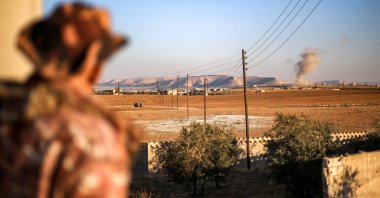 A fighter of the Syrian National Army (SNA) watches a plume of smoke erupt from bombardment at a position near the Tishrin Dam amid clashes with the PKK/YPG terrorists in Manbij, northern Aleppo province, Syria, Jan. 10, 2025. (AFP Photo)