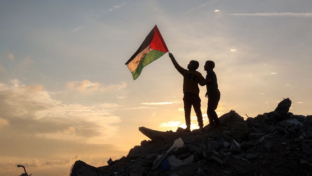 A boy runs with a Palestinian flag atop a mound of rubble at a camp for people displaced by Israel&#039;s attacks in Bureij in the central Gaza Strip, Jan. 17, 2025. (AFP Photo)