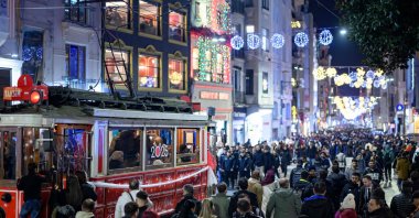 People walk past a historic tram on Istiklal Street on New Year's Eve, Istanbul, Türkiye, Dec. 31, 2024. (AFP Photo)