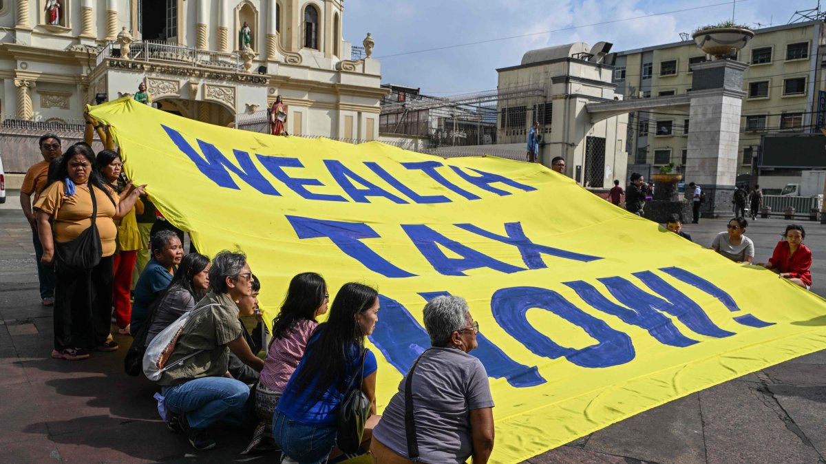 Members of an environmental group hold a banner reading &quot;Wealth Tax Now&quot; during a demonstration to highlight the issues of poverty and inequality in the region, which coincides with the opening day of the World Economic Forum (WEF) in Davos, Manila, Philippines, Jan. 20, 2025. (AFP Photo)