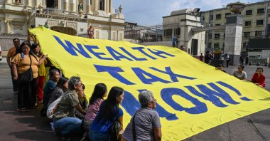 Members of an environmental group hold a banner reading &quot;Wealth Tax Now&quot; during a demonstration to highlight the issues of poverty and inequality in the region, which coincides with the opening day of the World Economic Forum (WEF) in Davos, Manila, Philippines, Jan. 20, 2025. (AFP Photo)
