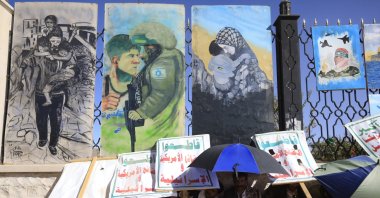 Houthi supporters take shelter from the sun beneath pro-Palestinian artworks on display on a fence during a pro-Palestine rally following the Israel-Hamas cease-fire deal, in Sana&#039;a, Yemen, Jan. 17, 2025. (EPA Photo)