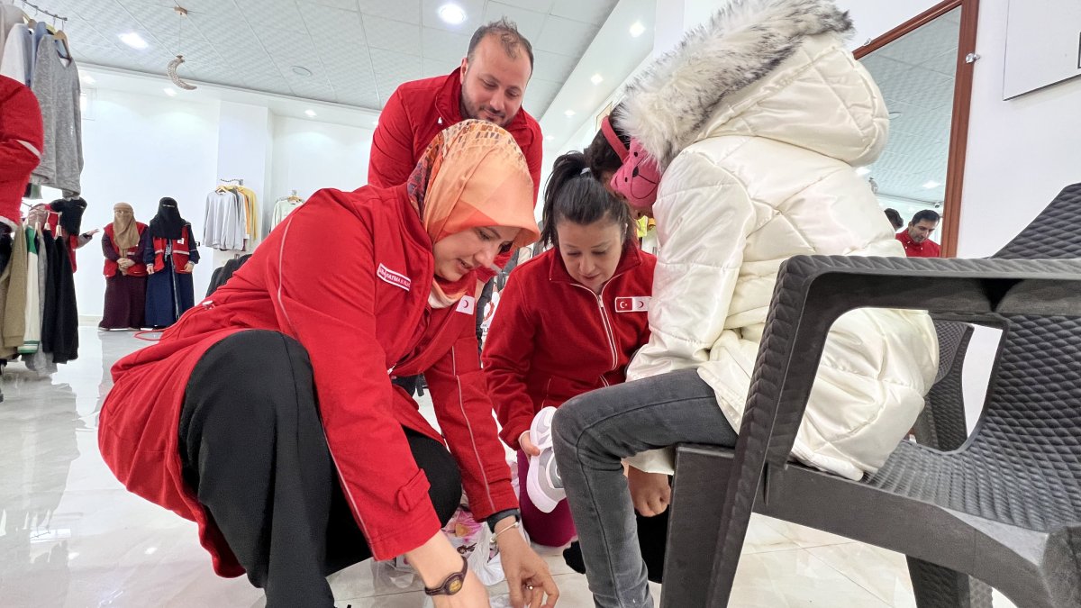 Turkish Red Crescent (Kızılay) President Fatma Meriç Yılmaz helps a Syrian child put on her shoes at the center established by Kızılay to aid Syria’s war victims, Idlib, northern Syria, Dec. 22, 2024. (AA Photo)