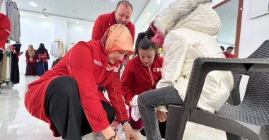 Turkish Red Crescent (Kızılay) President Fatma Meriç Yılmaz helps a Syrian child put on her shoes at the center established by Kızılay to aid Syria’s war victims, Idlib, northern Syria, Dec. 22, 2024. (AA Photo)