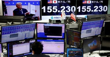 A screen broadcasting live footage of U.S. President Donald Trump presenting an executive order during the inaugural parade while other screens displaying the current Japanese yen exchange rate against the U.S. dollar are seen at a dealing room of the foreign exchange trading company Gaitame.com, Tokyo, Japan, Jan. 21, 2025. (Reuters Photo)