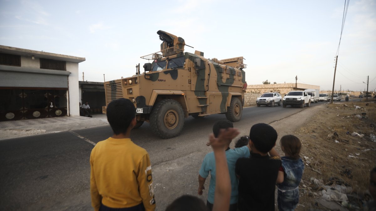 Children wave as a Turkish military convoy drives through the village of Urum al-Jawz, Idlib, Syria, Oct. 20, 2020. (AP Photo)