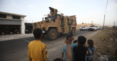 Children wave as a Turkish military convoy drives through the village of Urum al-Jawz, Idlib, Syria, Oct. 20, 2020. (AP Photo)