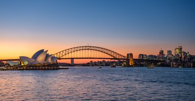 A view of Sydney Harbour, featuring the Sydney Opera House and Sydney Harbour Bridge, taken from Mrs Macquarie&#039;s Chair at sunset. (Shutterstock Photo)