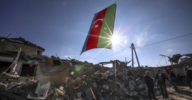 Azerbaijan&#039;s national flag flies over destroyed houses in a residential area that was hit by rocket fire from Armenian forces during the First Karabakh War, Ganja, Azerbaijan, Oct. 22, 2020. (AP Photo)