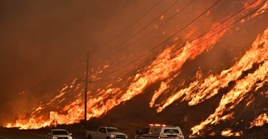 Emergency vehicles are on the side of the road as flames from the Hughes Fire race up the hill in Castaic, a northwestern neighborhood of Los Angeles, California, U.S., Jan. 22, 2025. (AFP Photo)
