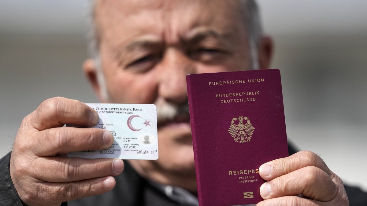 Mehmet Ali Yiğit, who has been living in Germany for more than 50 years, shows his German passport and Turkish ID after he voted at the Gruga Hall, Essen, Germany, April 27, 2023. (AP Photo)