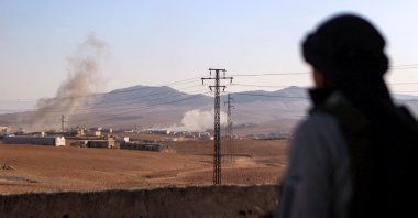 A Syrian National Army (SNA) fighter watches a plume of smoke erupt from bombardment at a position near the Tishrin Dam in the vicinity of Manbij, Syria, Jan. 10, 2025. (AFP Photo)