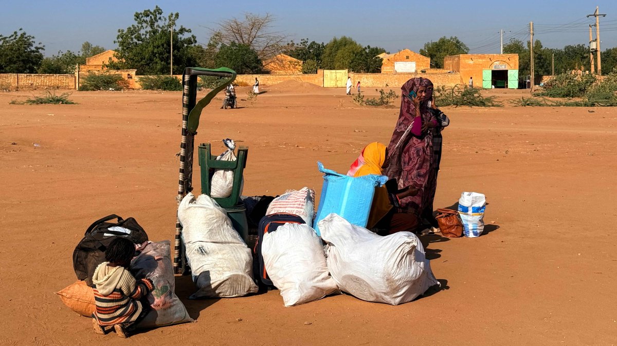 A child and a woman wait next to their belongings as war-displaced people return to Wad Madani in the Jazira state, Sudan, Feb. 6, 2025. (AFP Photo)