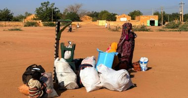 A child and a woman wait next to their belongings as war-displaced people return to Wad Madani in the Jazira state, Sudan, Feb. 6, 2025. (AFP Photo)