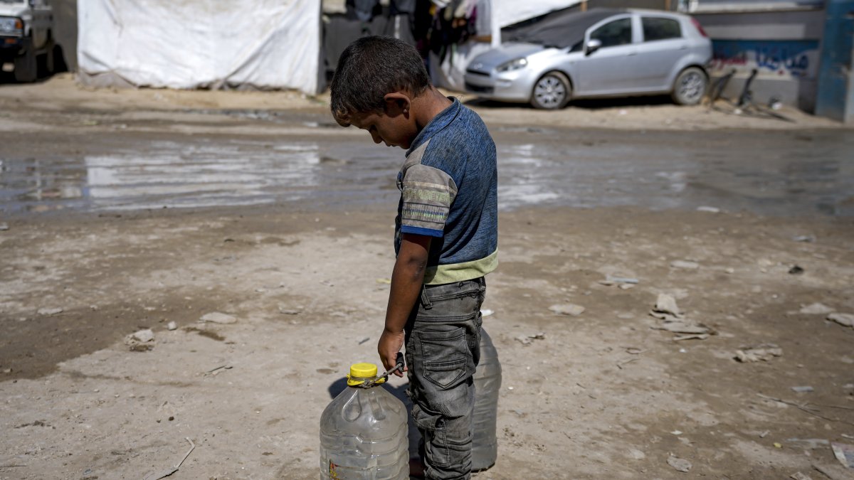 A displaced child carries filled water bottles at a makeshift tent camp, Deir al-Balah, Gaza Strip, Palestine, Aug. 29, 2024. (AP Photo)