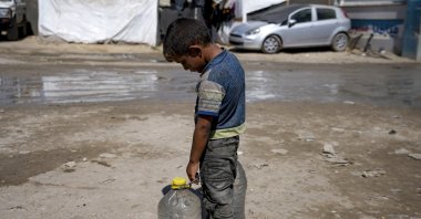 A displaced child carries filled water bottles at a makeshift tent camp, Deir al-Balah, Gaza Strip, Palestine, Aug. 29, 2024. (AP Photo)