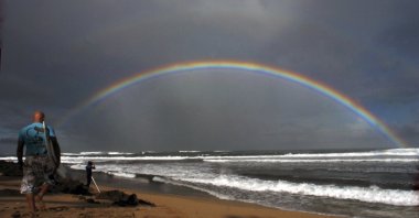 Professional surfers make their way to the water while a large rainbow crosses the ocean during the Pro Hawaii surfing contest at Ali&#039;i Beach, Haleiwa, Hawaii, U.S., Nov. 18, 2005. (AP Photo)