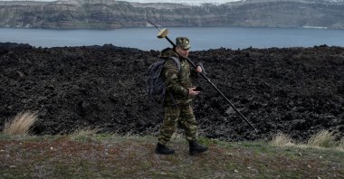 Santorini island is seen in the background as a member of Greece’s military geographical team proceeds to conduct geological measurements, to evaluate potential structural changes due to the ongoing seismic activity on the volcanic island of Nea Kameni, Greece, Feb. 10, 2025. (Reuters Photo)